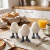 Ein cooler Roboter Eierbecher aus dem 3D-Drucker, in dem ein weisses Ei steckt, dekoriert auf einem morgendlichen Frühstückstisch mit Brot und Orangensaft.