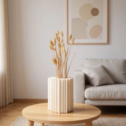 Eine weisse organische Korallen Vase aus dem 3D-Drucker, die stilvoll mit getrocknetem Pampasgras auf einem hellen Holztisch im Wohnzimmer dekoriert ist.