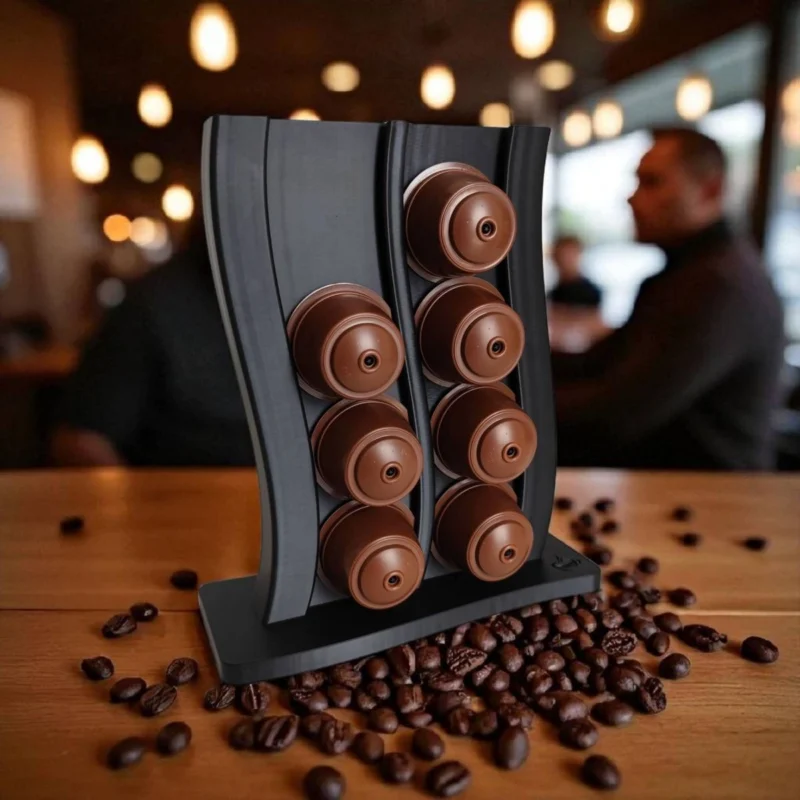 Ein dunkelgrauer Dolce Gusto Kapselhalter aus dem 3D-Drucker im dynamischen Wellen-Design, der beidseitig mit braunen Kaffeekapseln befüllt auf einer Holzarbeitsfläche steht.