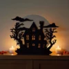 Ein beleuchteter Halloween Spukhaus Teelichthalter aus dem 3D-Drucker, der mit einem leuchtenden LED-Teelicht eine gruselige Stimmung auf einer dunklen Holzkommode verbreitet.