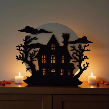 Ein beleuchteter Halloween Spukhaus Teelichthalter aus dem 3D-Drucker, der mit einem leuchtenden LED-Teelicht eine gruselige Stimmung auf einer dunklen Holzkommode verbreitet.