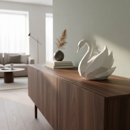 Eine weisse Low Poly Schwan Skulptur aus dem 3D-Drucker, die elegant auf einem dunklen Sideboard im modernen Wohnzimmer dekoriert ist.