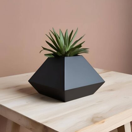 Ein dunkelgrauer Pyramiden Blumentopf im minimalistischen Design, bepflanzt mit einer kleinen, grünen Sukkulente, auf einem hellen Holztisch.