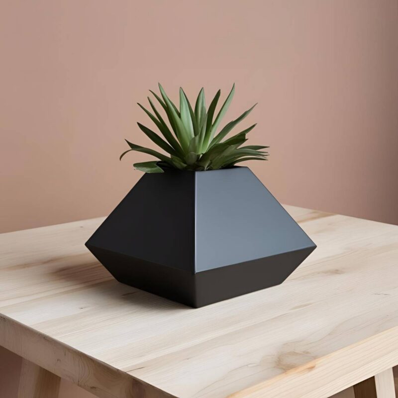 Ein dunkelgrauer Pyramiden Blumentopf im minimalistischen Design, bepflanzt mit einer kleinen, grünen Sukkulente, auf einem hellen Holztisch.