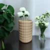 Eine beige Boho Bubble Vase aus dem 3D-Drucker, die stilvoll mit weissen Blumen auf einem dunklen Holztisch präsentiert wird.