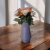 Nahaufnahme der ägyptisch inspirierten Vase, die auf einem rustikalen Holztisch steht und elegant mit frischen Rosen dekoriert ist.