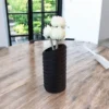 Eine schwarze moderne Swirl Vase aus dem 3D-Drucker, die stilvoll mit weissen Blumen auf einem rustikalen Holztisch dekoriert ist.