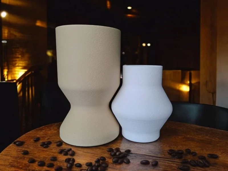 Ein minimalistisches Vasen Set aus dem 3D-Drucker in den Farben Beige und Weiss, das auf einem rustikalen Holztisch perfekt ineinandergreift.