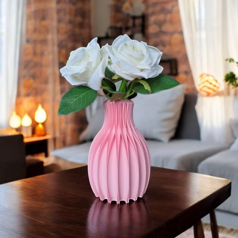 Eine rosa Design Vase Facetta aus dem 3D-Drucker mit markanter, facettenreicher Struktur, die auf einem dunklen Holztisch dekoriert ist.