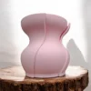 Eine rosa skulpturale Design Vase Aera aus dem 3D-Drucker mit doppelwandiger Struktur, die elegant auf einer rustikalen Holzscheibe präsentiert wird.
