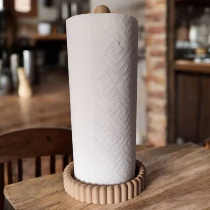 Ein beigefarbener moderner Küchenrollenhalter aus dem 3D-Drucker, der eine weisse Papierrolle stilvoll auf einer edlen Holzarbeitsplatte präsentiert.