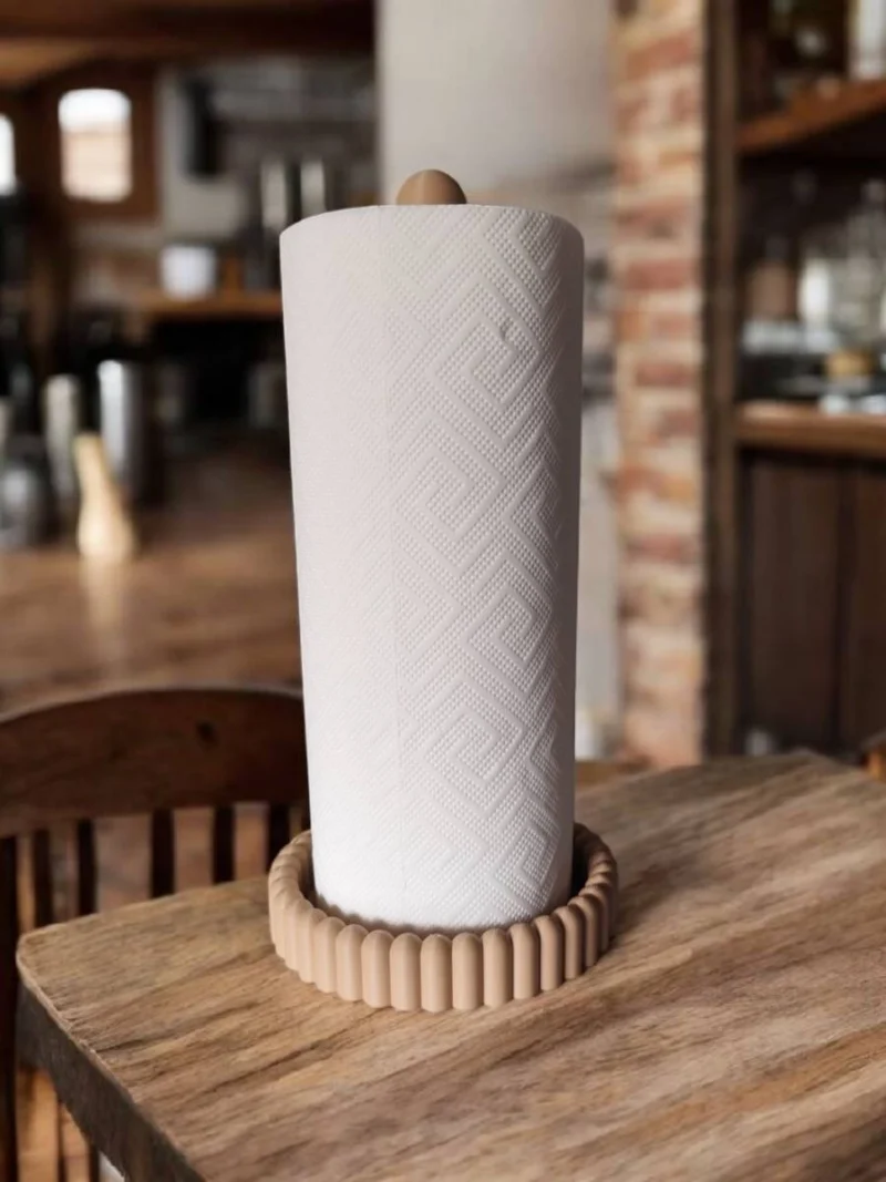 Ein beigefarbener moderner Küchenrollenhalter aus dem 3D-Drucker, der eine weisse Papierrolle stilvoll auf einer edlen Holzarbeitsplatte präsentiert.
