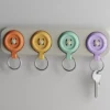 Ein elegantes Design Schlüsselbrett aus dem 3D-Drucker an einer Wand, an dem bunte Knopf-Schlüsselanhänger in sanften Farben hängen.