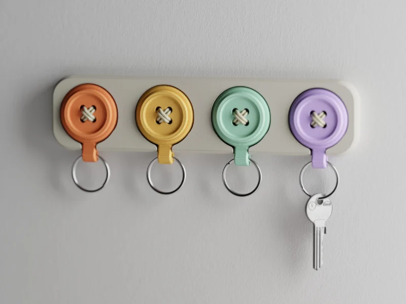 Ein elegantes Design Schlüsselbrett aus dem 3D-Drucker an einer Wand, an dem bunte Knopf-Schlüsselanhänger in sanften Farben hängen.